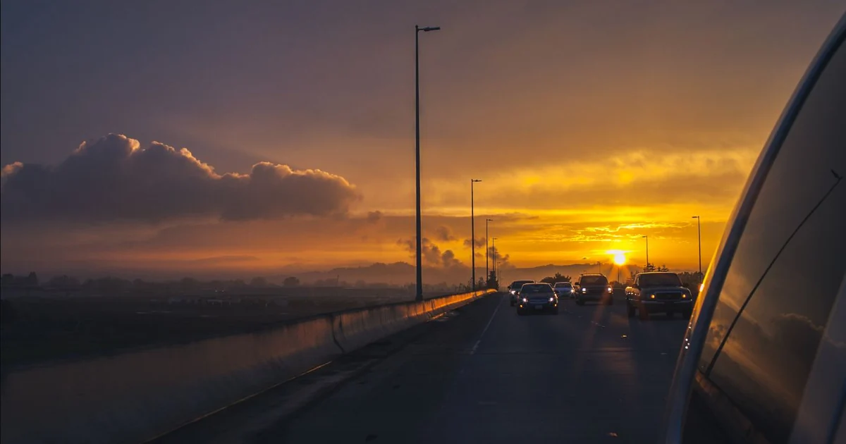Gün batımında akan trafikteki otomobiller